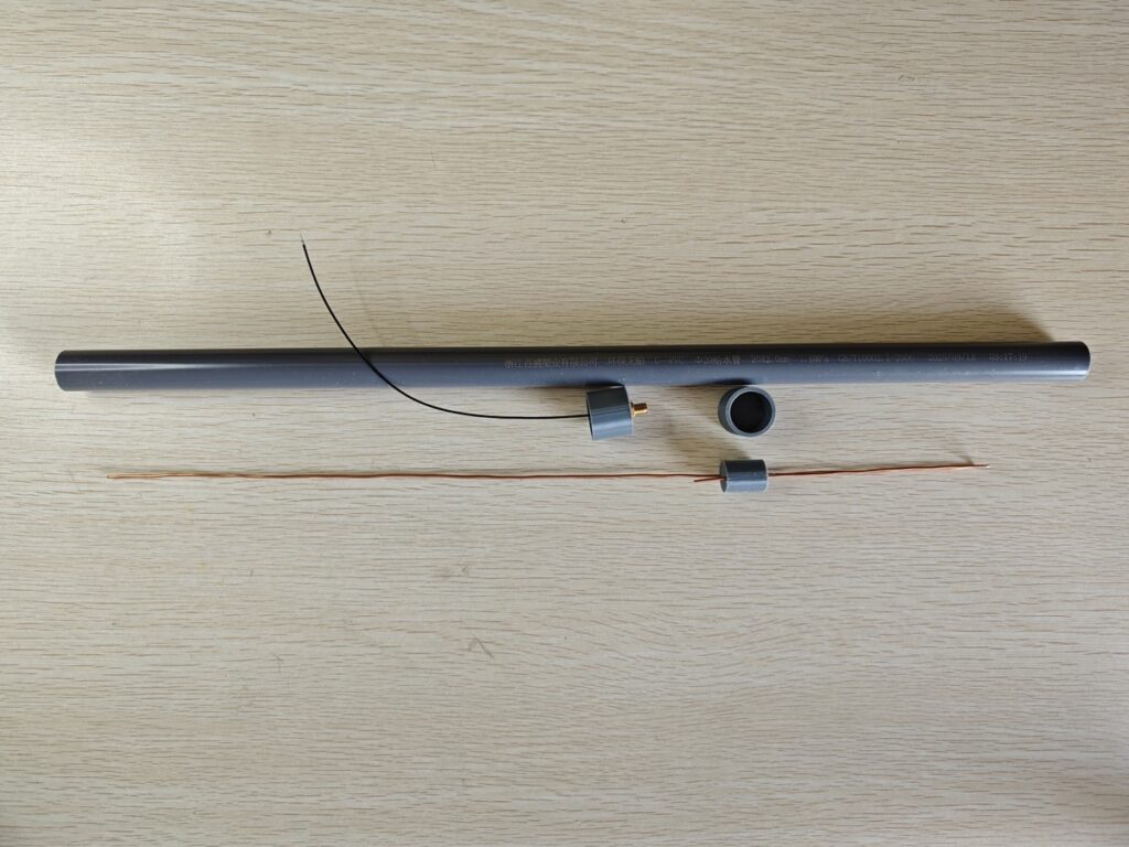 Homemade J-Pole antenna parts including PVC pipe, copper wire, spacers, and coax pigtail