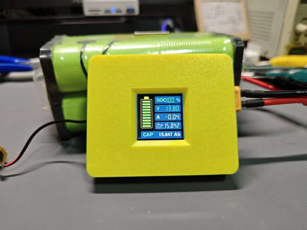 Battery meter in a yellow enclosure showing a large battery gauge page while connected to a 4S LiFePO4 pack.
