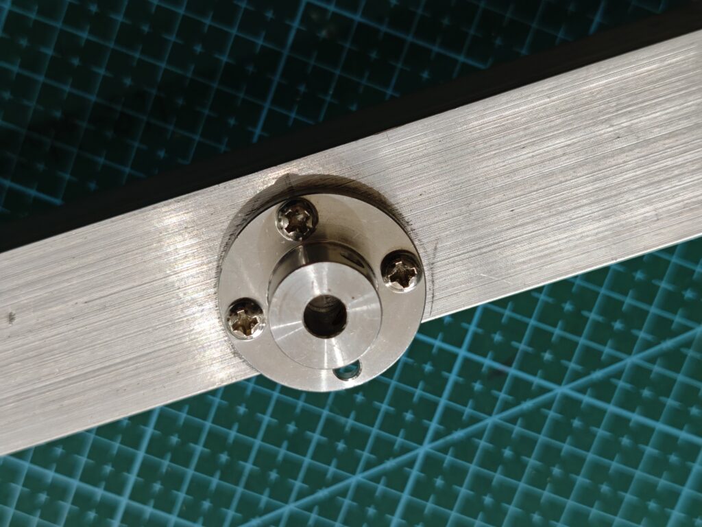 Close-up shot of a metal flange coupling mounted to an aluminum angle bar for an amateur radio antenna rotator, secured with three screws due to the limited width of the angle bar.